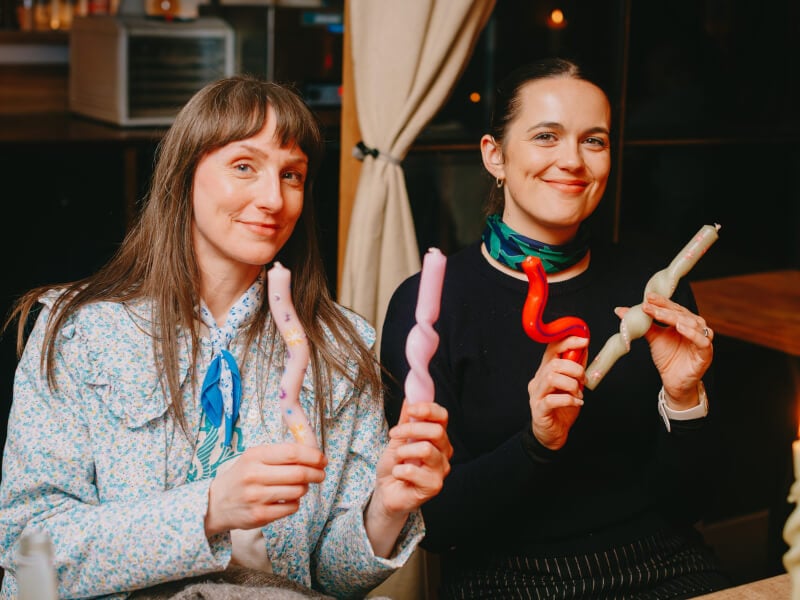 Two women holding up bendy candlesticks